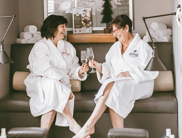 Two women enjoying champagne as they relax at the spa before their pedicures