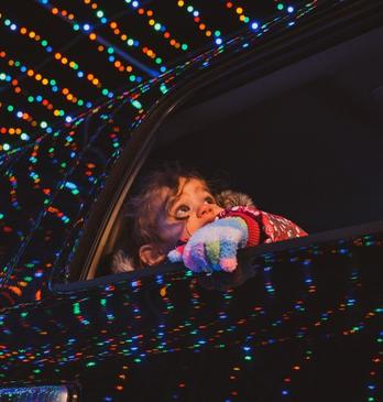 Young girl looking out of car window at glistening light displays