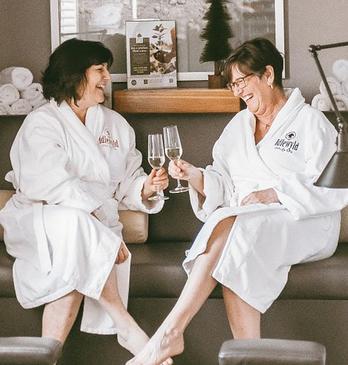 Two women enjoying champagne as they relax at the spa before their pedicures