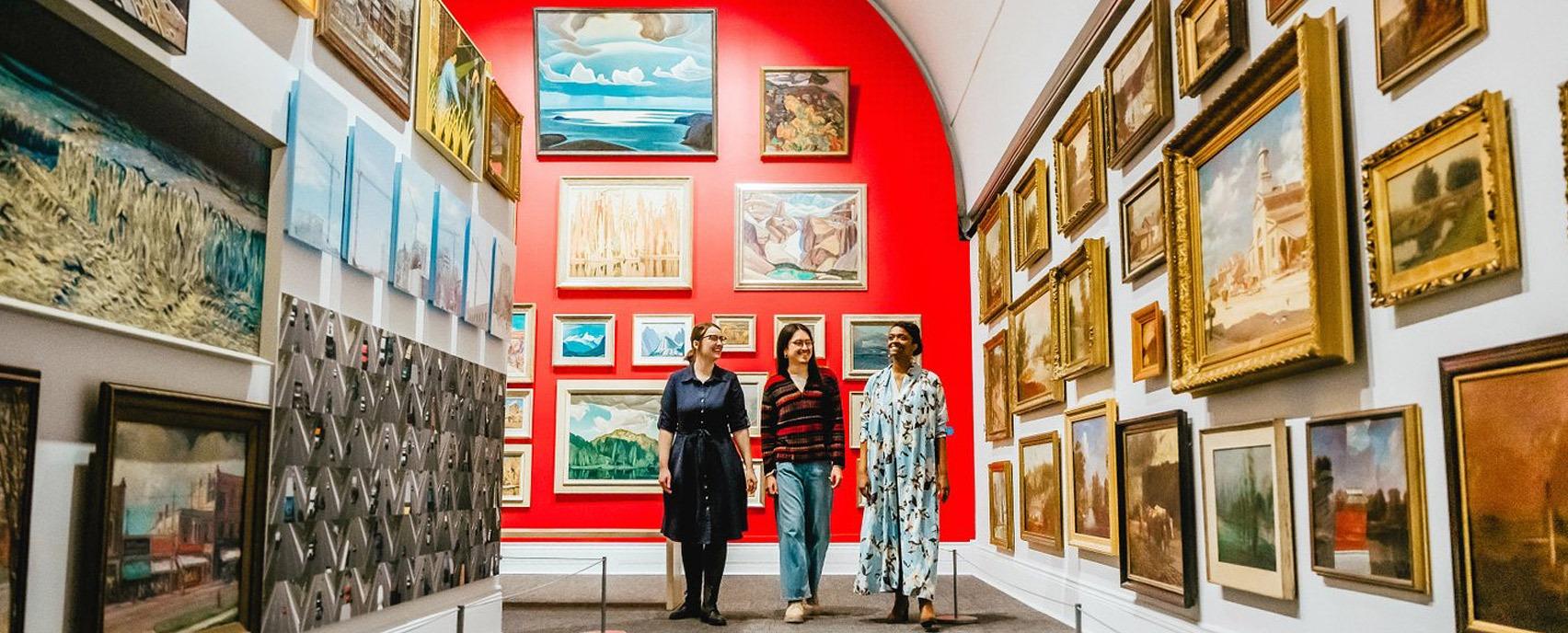 Three friends looking at various paintings on display from the Group of Seven in Museum London located in London, Ontario