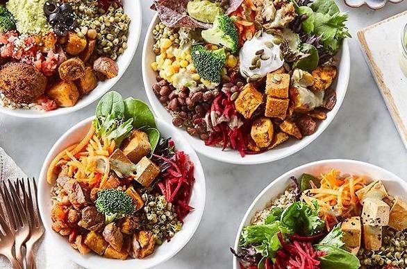 Various plant based dishes on display on a marble table top with cutlery