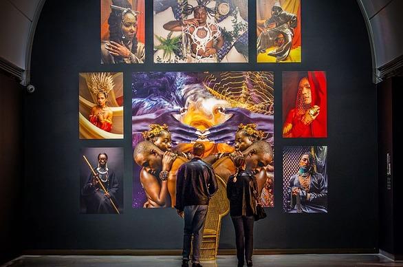 Two people looking at vibrant works of art hanging on the walls of Museum London, located in London, Ontario