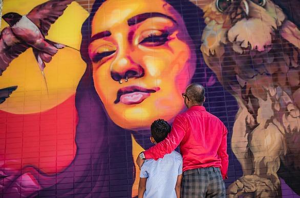 A father and son observing a large mural found at Market Lane in downtown London, Ontario