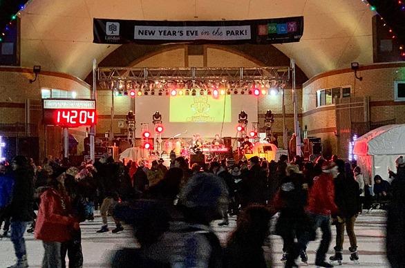 A large group of people skating outdoors at Victoria Park while a band plays live music on stage on New Years Eve in London, Ontario