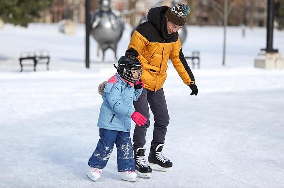 A father and his daughter skating at an outdoor skating rink in Victoria Park located in London, Ontario