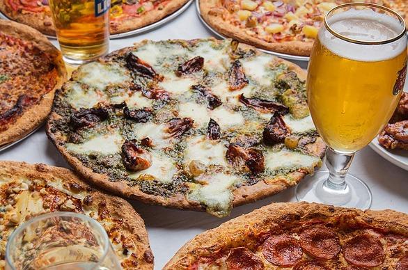 A table top view with several pizzas and a glass of beer from Pizza Projekt, located in London, Ontario