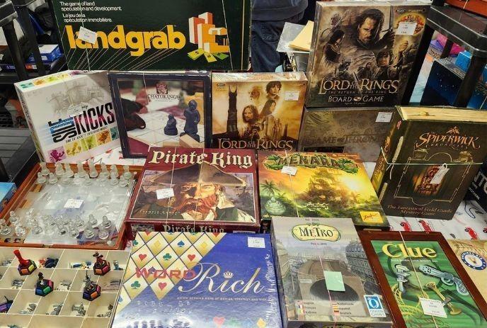 Various board games including 'Lord of the Rings,' 'Pirate King,' 'Clue,' and 'Metro,' displayed on a table.