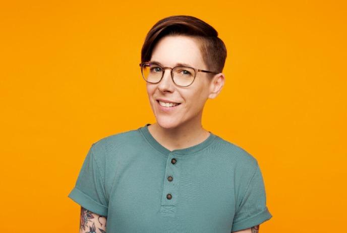 DeAnne Smith smiling for the camera in front of an orange background.