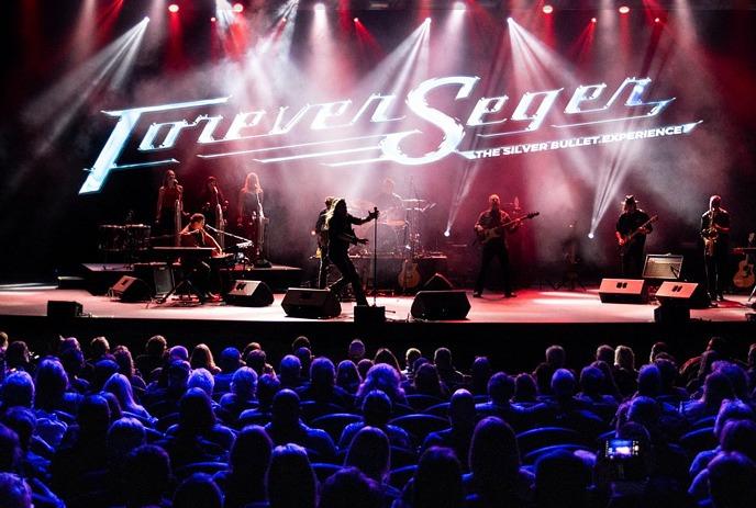 Forever Seger tribute band performing live on stage to a large crowd under red and blue lights in the background.