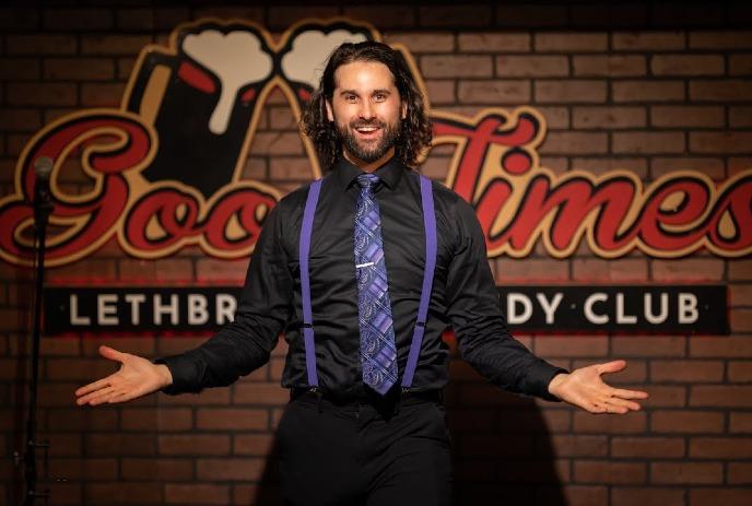 Alex Mackenzie performing at the Good Times Lethbridge Comedy Club in a black shirt with purple suspenders and tie.