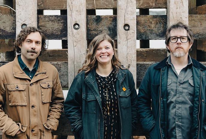 The 3 band members of 'The Once', standing in front of a red wall with blank expressions.