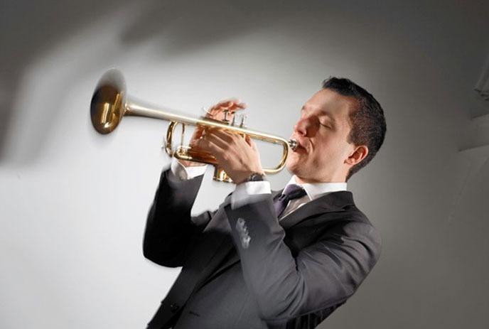 A man playing the trumpet in front of a white background.