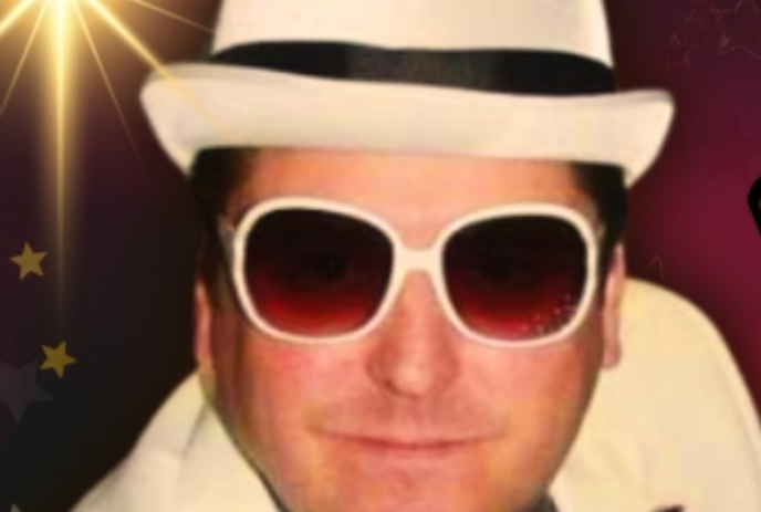 Close-up image of Elton John tribute actor wearing a white hat and white sunglasses.