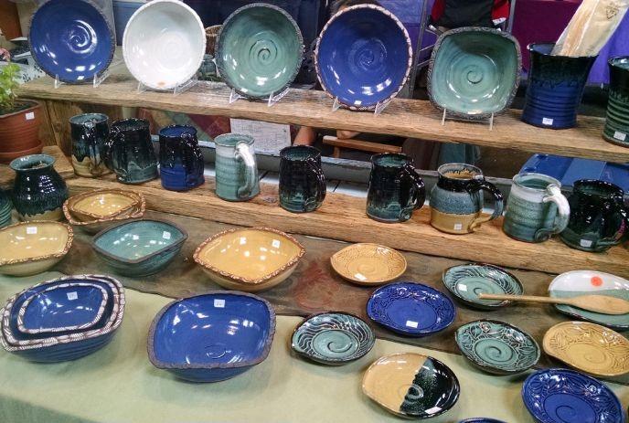 A collection of hand-crafted pottery, including plates, mugs, and bowls, in earthy and vibrant colors.