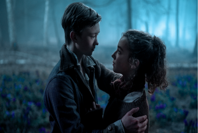 Two young people embracing in the woods at dusk.