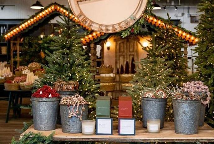 Stalls outside of a Christmas market with Christmas trees and decorations.