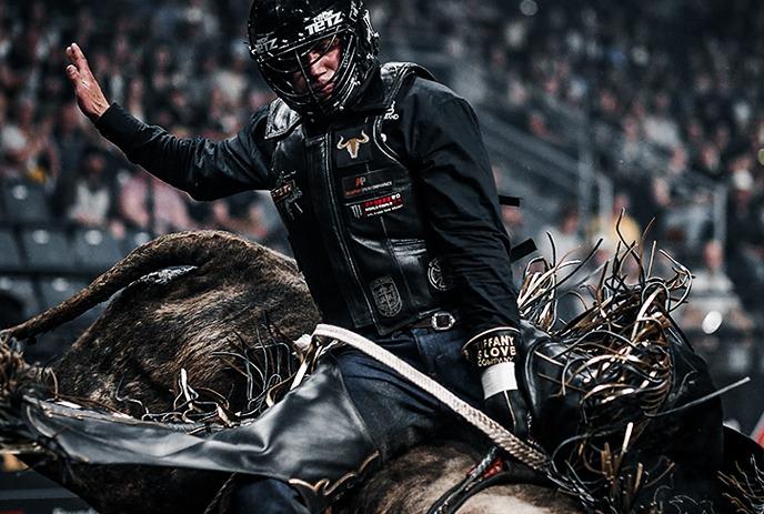 A person riding a bull at a rodeo event.