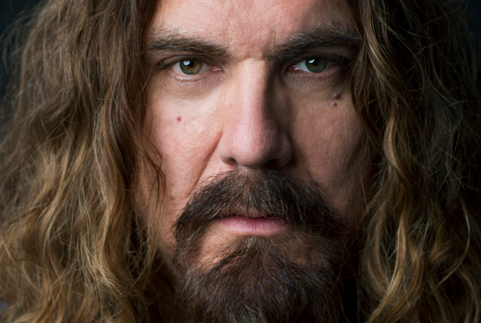 A close up of a mans face with long hair and a beard.