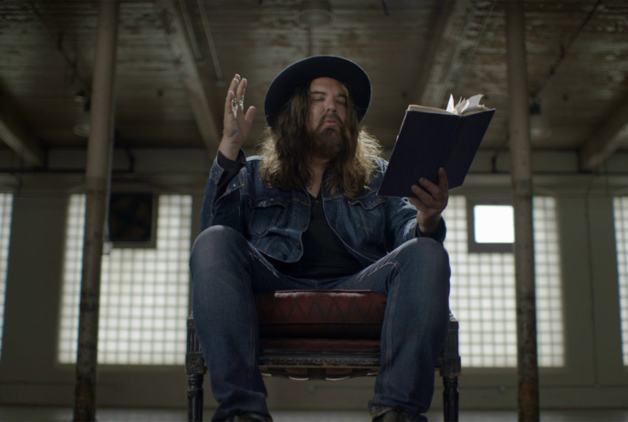 Tom Wilson reading a book in a dimly lit room.