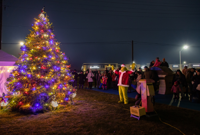 People standing around a decorated Christmas tree outside at nighttime.