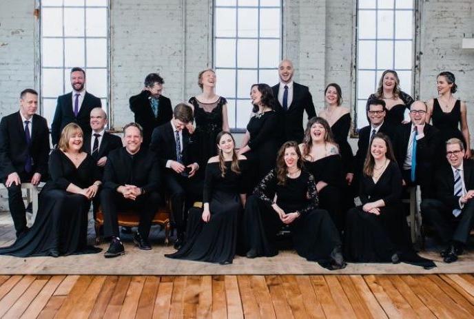 Large group of singers dressed in black posing for a group photo.