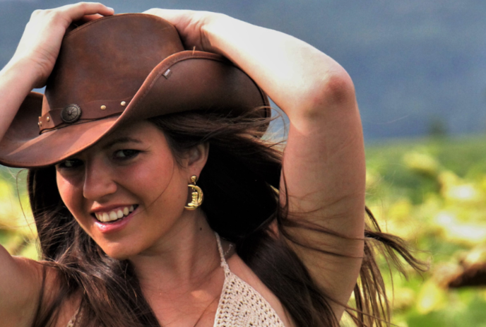 Shania Twain look-alike wearing a cowboy hat and holding her hands over her head