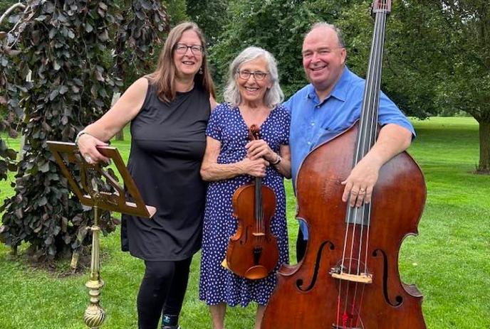 The Hysen Trio posing with their instruments outside on a lawn.