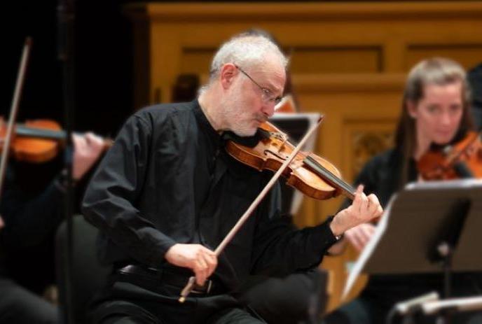 Person wearing black playing the violin on stage.