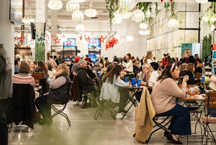 Lots of people sitting down and eating in a large area.