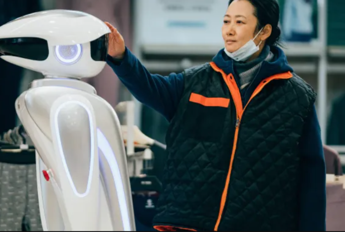 Person standing in front of a robot, with their hand touching the robot's