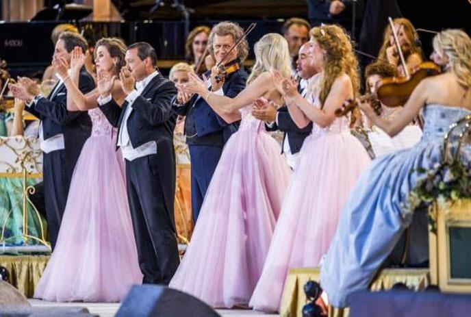 Formal dance with pink-gowned women, black-suited men, obscured faces, and an orchestra.