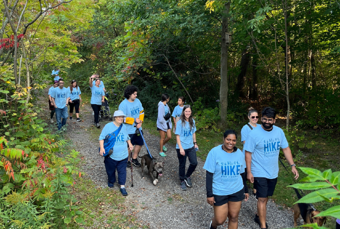 People wearing blue hike for hospice t-shirts, walking through the woods.