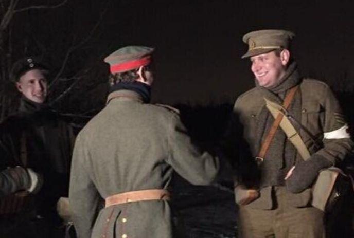 Two soldiers from opposing sides during wartime are seen exchanging smiles and shaking hands, symbolizing peace.