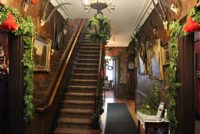 Victorian-style hallway at Eldon House decorated with festive greenery and historical artifacts for the holiday season.