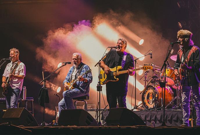 The band Bachman Turner-Overdrive performing live onstage with their instruments under smoke and lights.