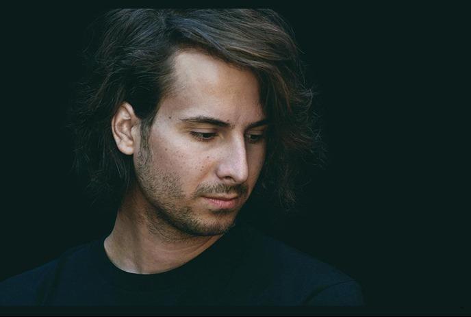 A headshot of Bobby Bazini, looking downwards against a black background.