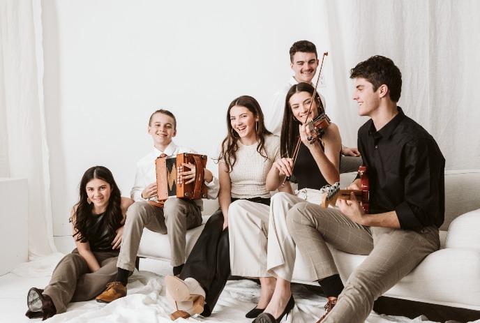 The Next Generation Leahy posing with their instruments in a relaxed, casual setting.