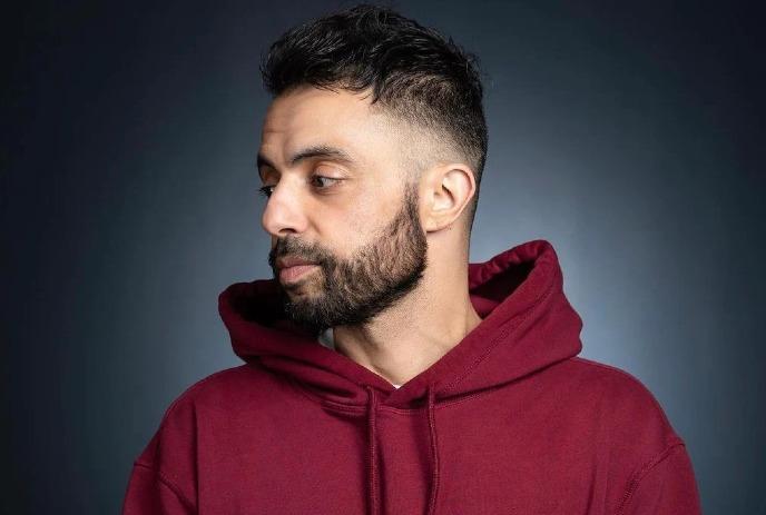 A headshot of Sammy Obeid, wearing a red sweater and looking sideways.