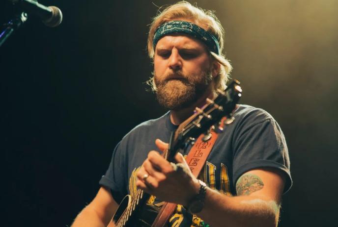 Charles Wesley Godwin wearing a headband on stage, performing guitar .