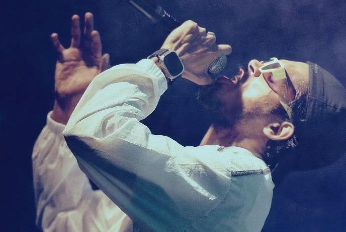 Dabzee performing on stage with a mic in his hand, singing while looking upwards.