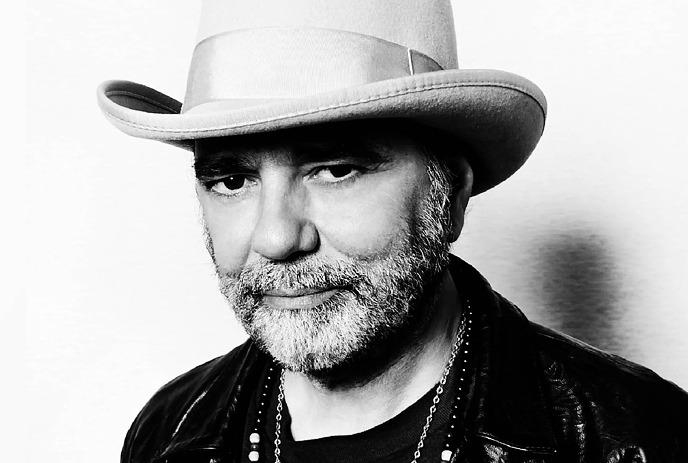 A black and white photograph of a Daniel Lanois wearing a white cowboy hat and black jacket.