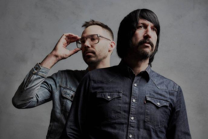 The two band members of Death From Above 1979 posing for the camera in front of a grey background.