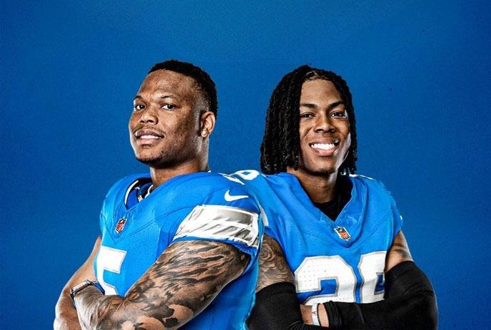 Two Detroit Lions players, standing side by side smiling, wearing their uniforms.