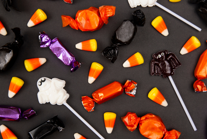 Various Halloween Candies spread out on a black surface.