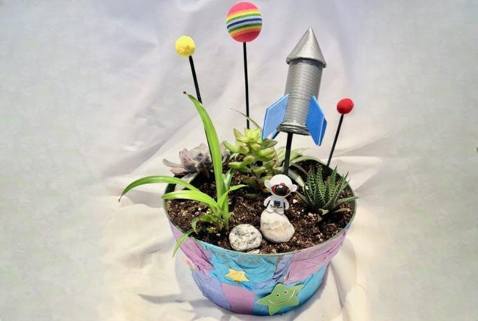 A colorful pot filled with various small succulent plants and decorative items.