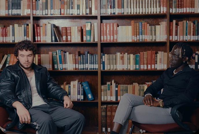 Two people sitting together inside of a library.