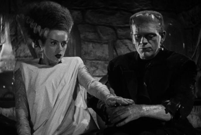 The Bride of Frankenstein and the monster sit together, tense and curious.