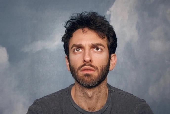 A headshot of Giamarco Soresi, staring upwards against a grey background.