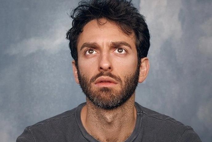 A headshot of Giamarco Soresi, staring upwards against a grey background.