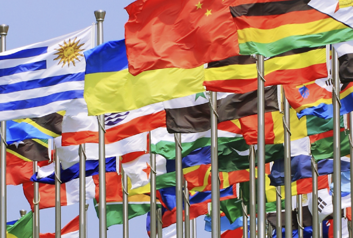 International flags wave in the breeze against a clear blue sky.